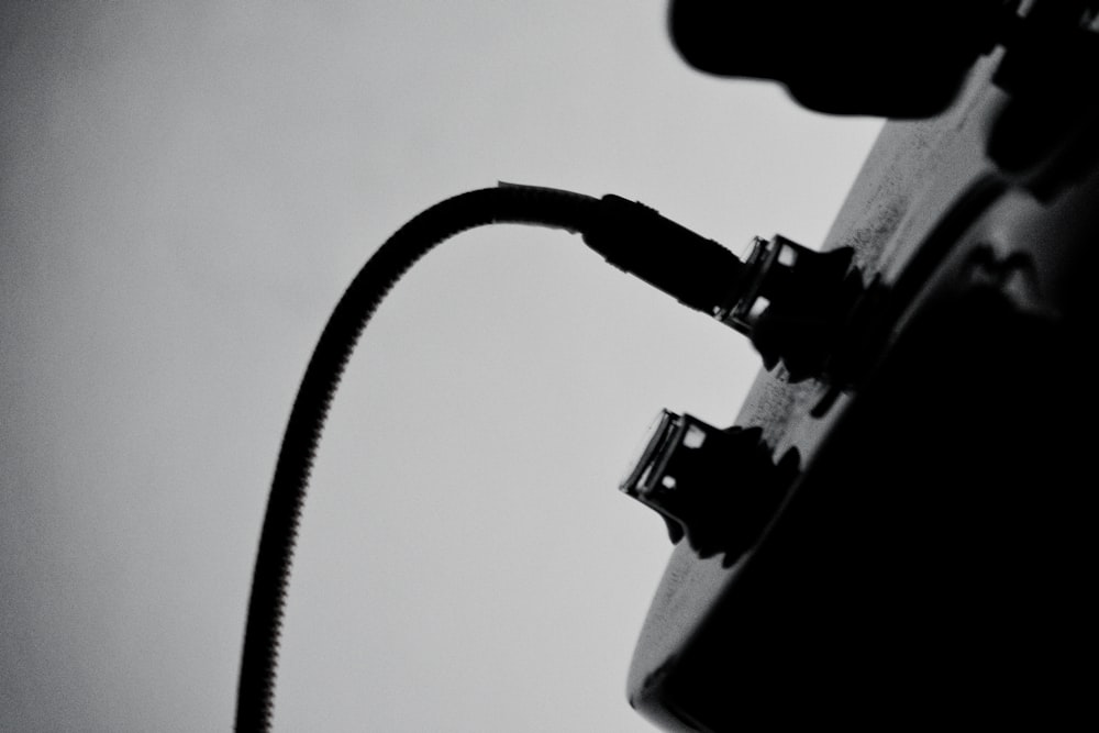 Uma foto em preto e branco de um fio conectado a uma guitarra