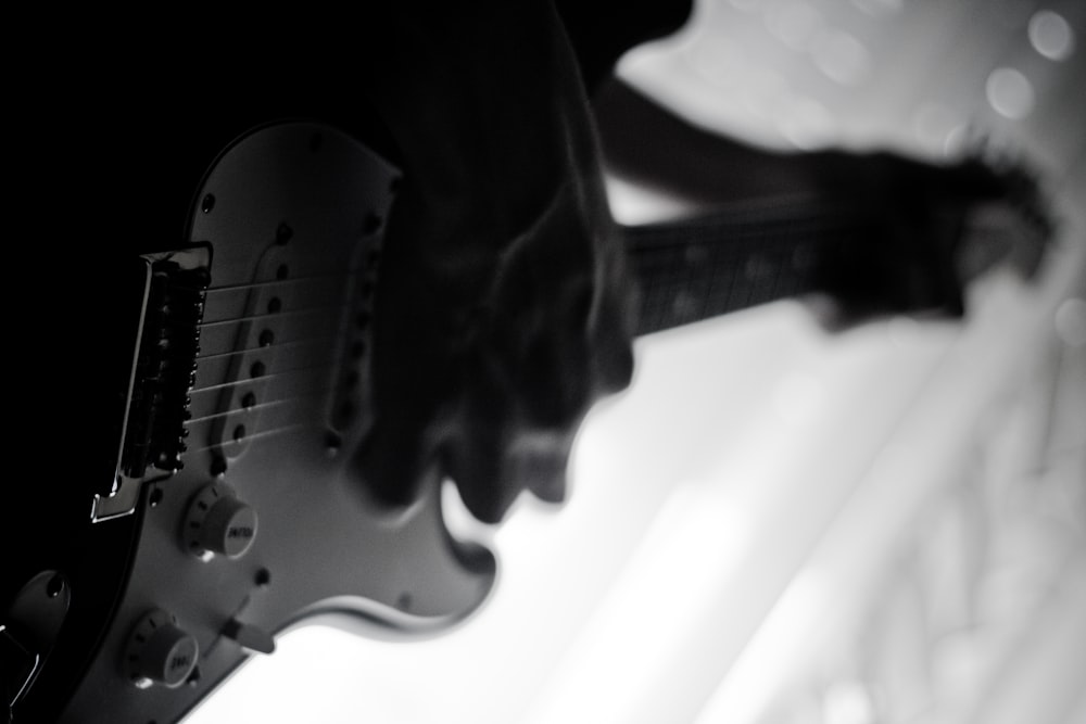 일렉트릭 기타를 연주하는 사람의 회색조 사진