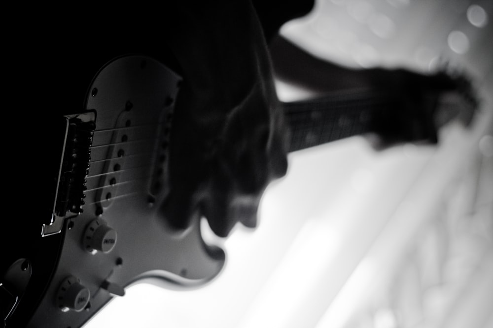 grayscale photo of person playing electric guitar