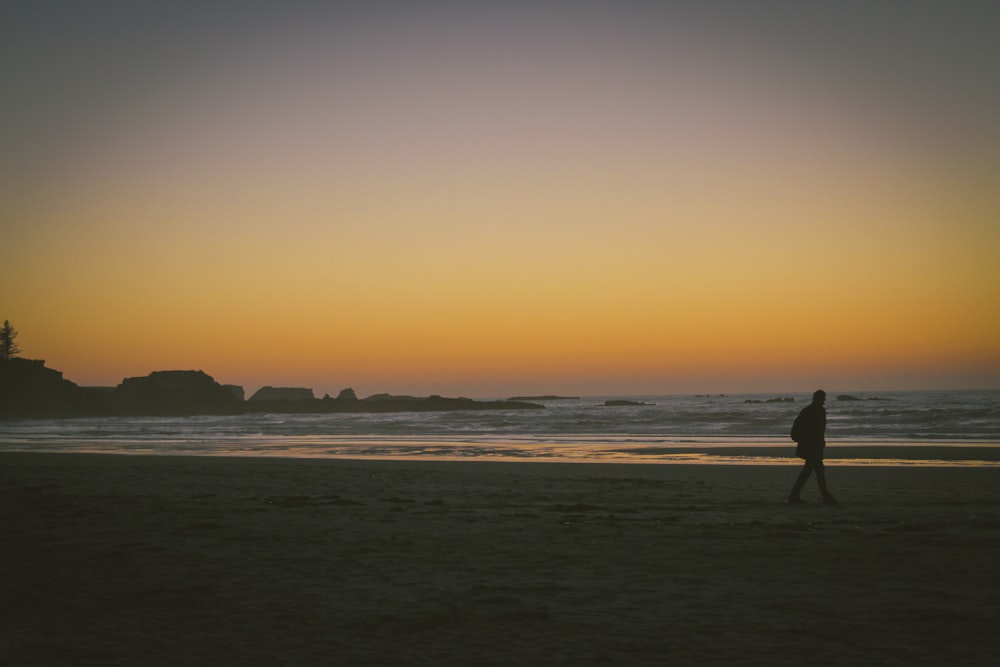 silhouette of person walking on seashore