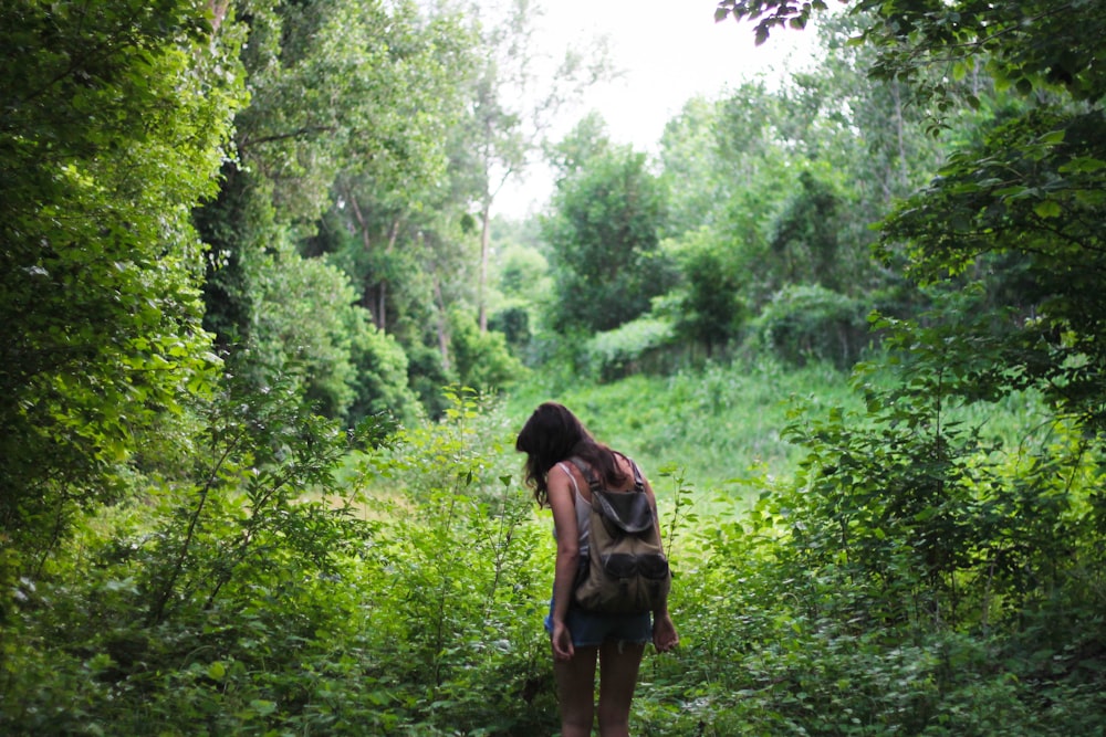 woman with backpack near green trees