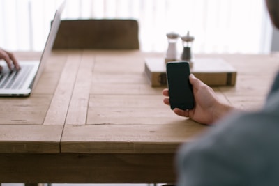 A close-up of a smartphone and laptop on a wooden table