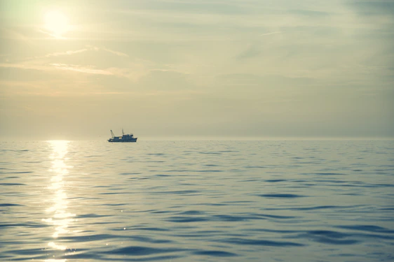 A serene sunrise over Lake Erie with a lone fishing boat cutting through the gentle waves.