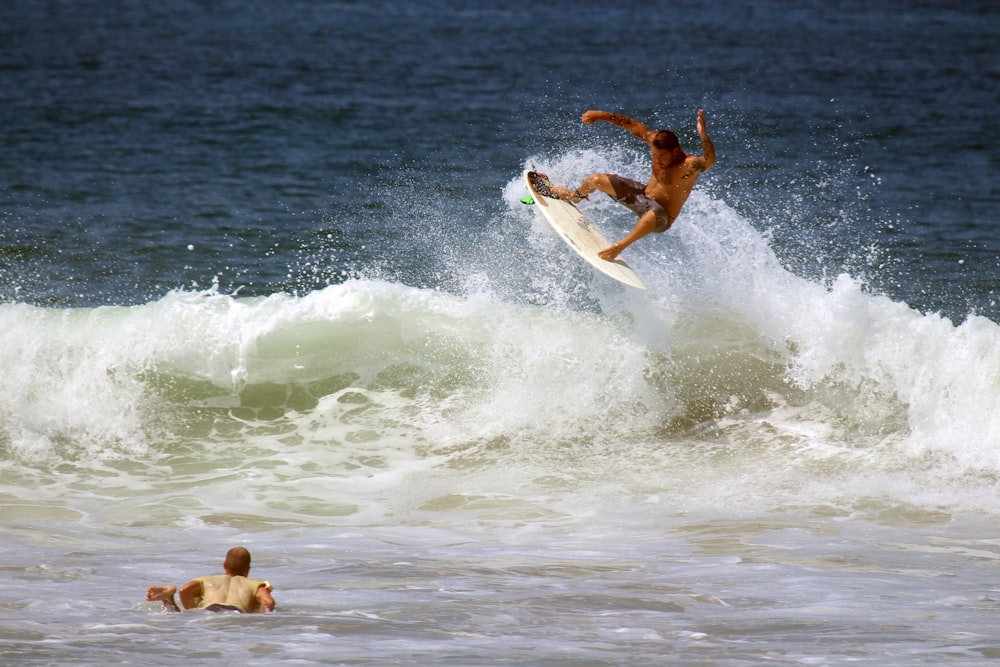 homme surfsurf sur la vague de l’océan pendant la journée