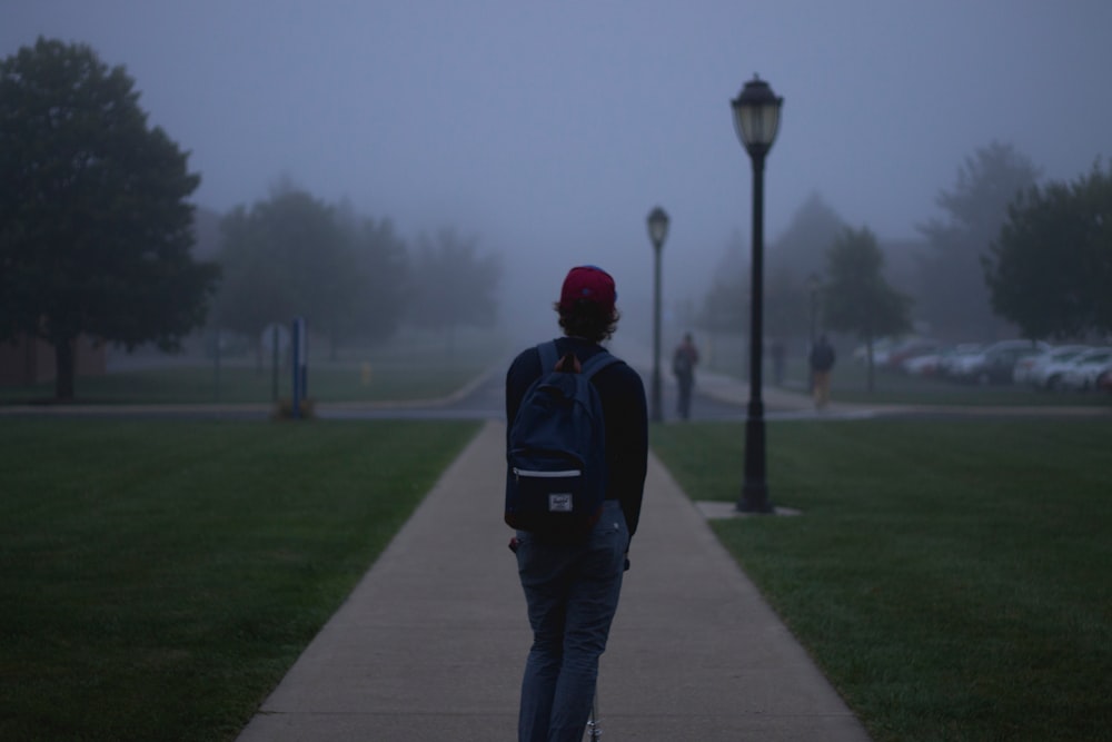 College student alone on a razor scooter on a foggy day