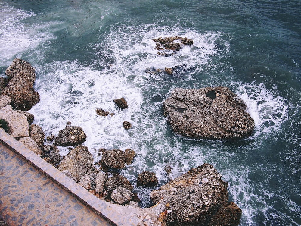 rock formations with crashing seashore at daytime