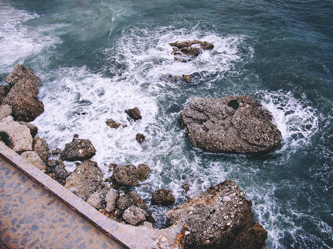 rock formations with crashing seashore at daytime