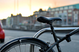 A sleek Veloza bike parked beside a city street at sunset, ready for a ride.