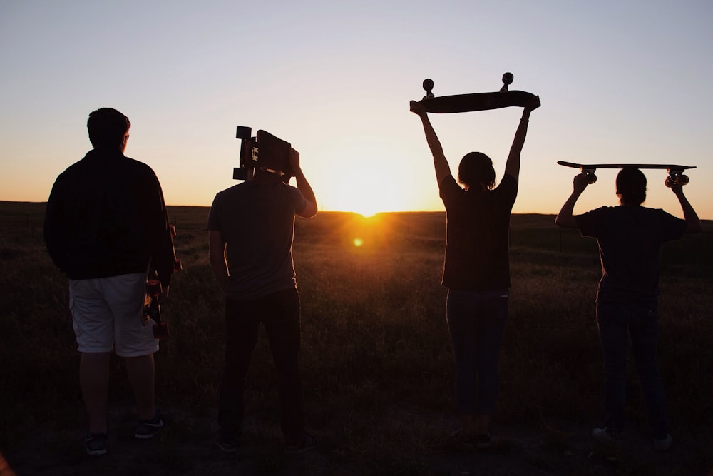 gruppo di persone che tengono skateboard sotto il tramonto