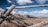 A rugged wooden fence stretching across a golden prairie under a wide blue sky.