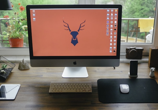 silver iMac on brown wooden table