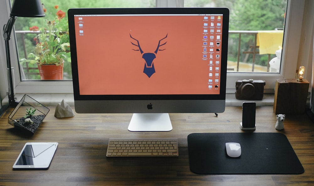 silver iMac on brown wooden table