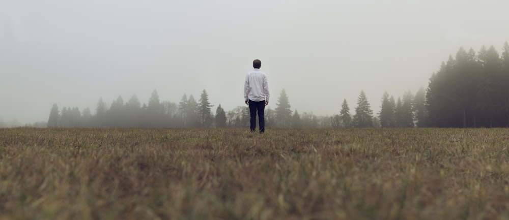 man standing in front of forest with fog