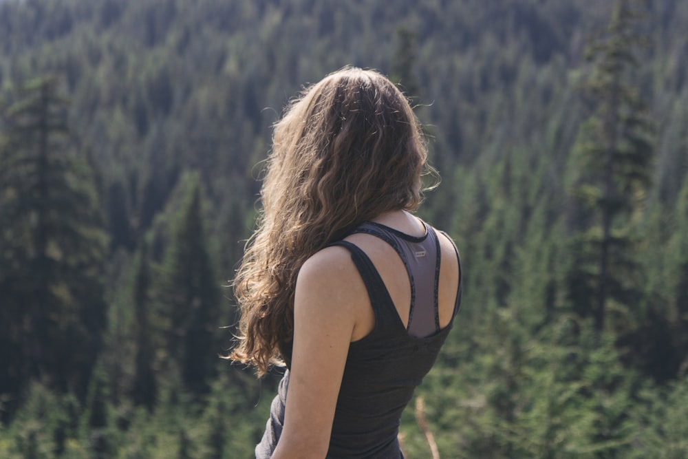 woman standing while watching green trees at daytime