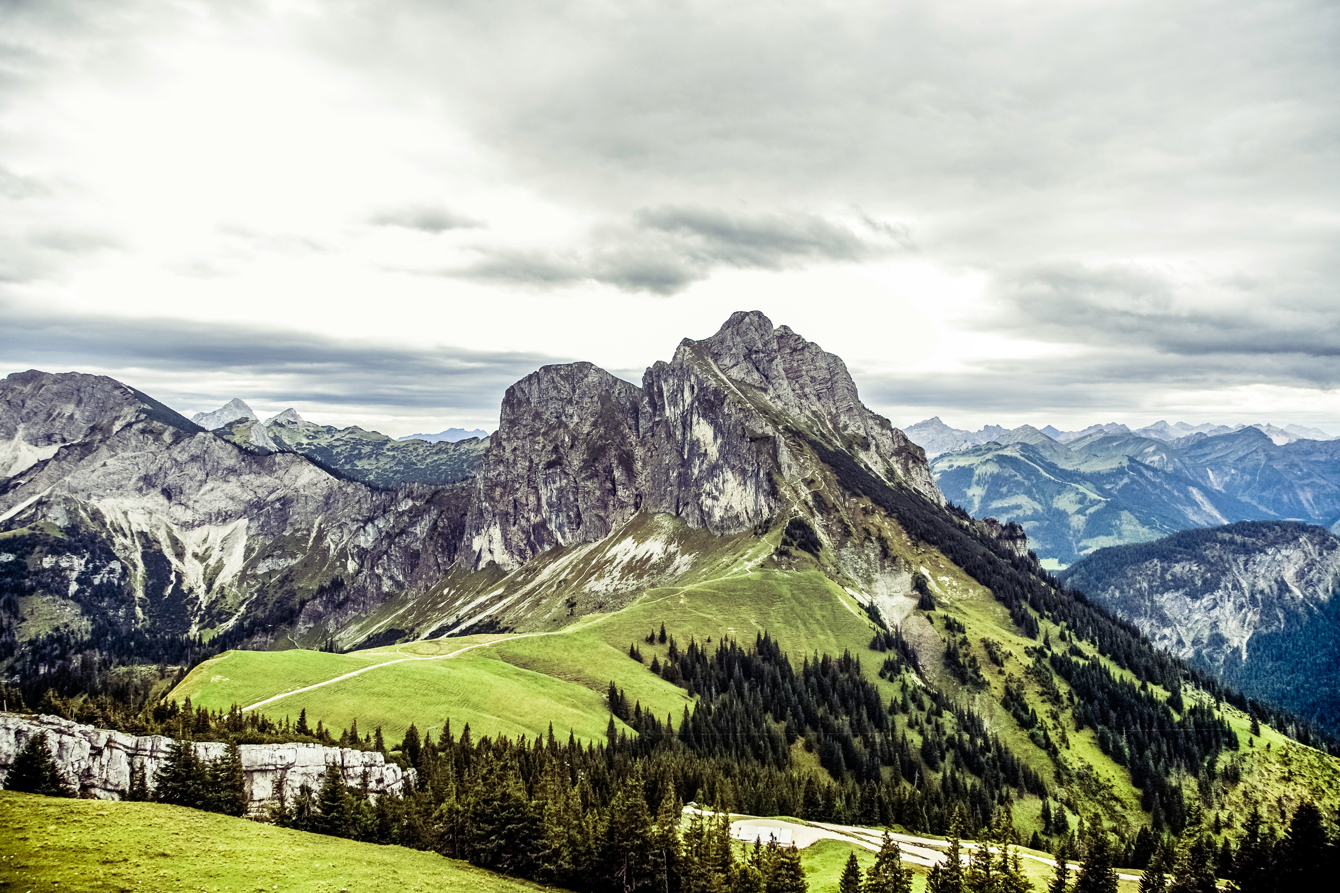 mountain covered by green grass and trees under white clouds