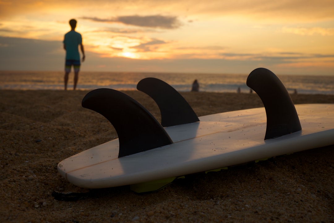 white and black surfboard on white sand during sunsetr