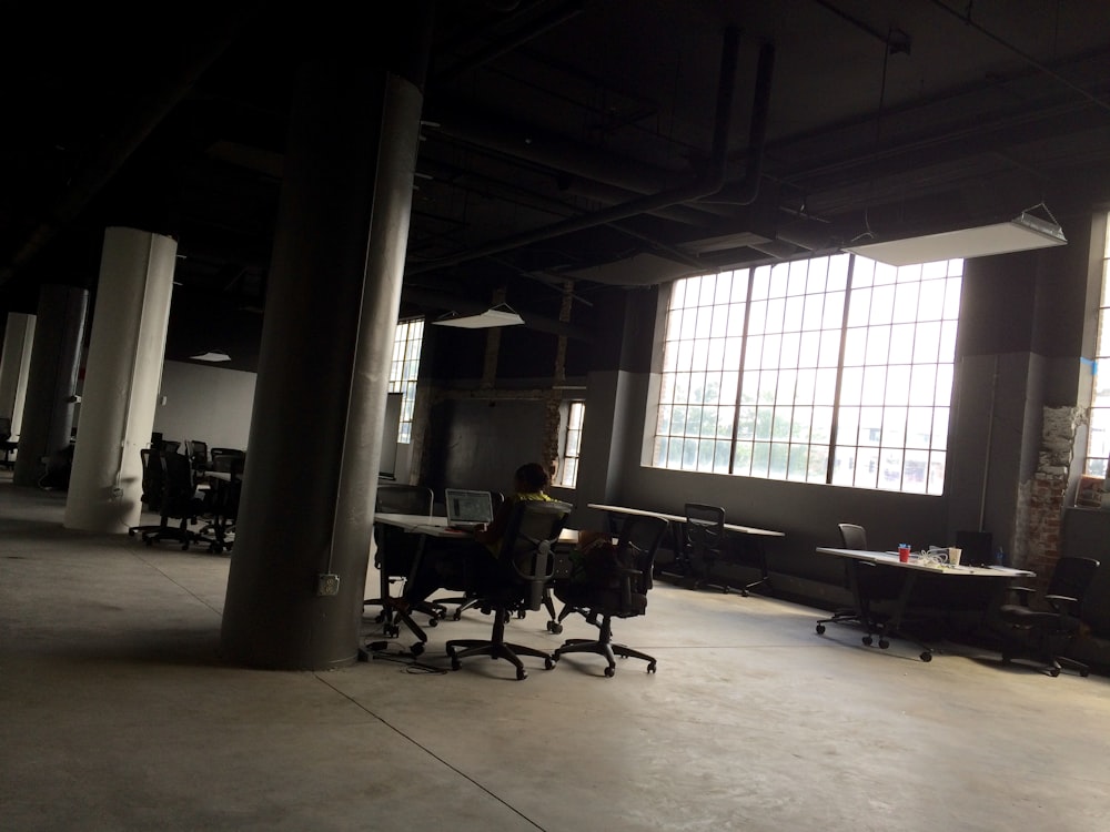 man sitting on chair facing table inside building