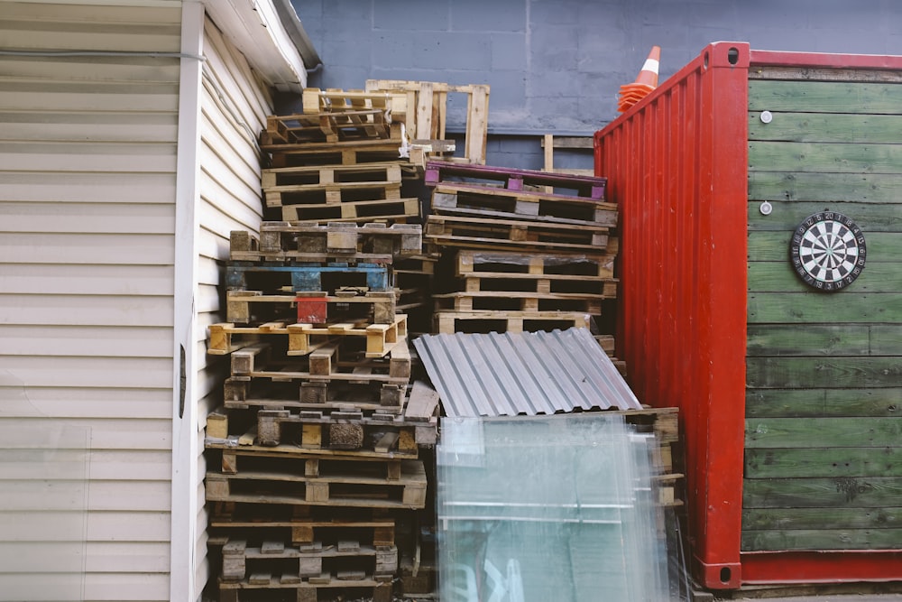 Lote de cajas de madera marrón entre el contenedor de envío rojo y verde