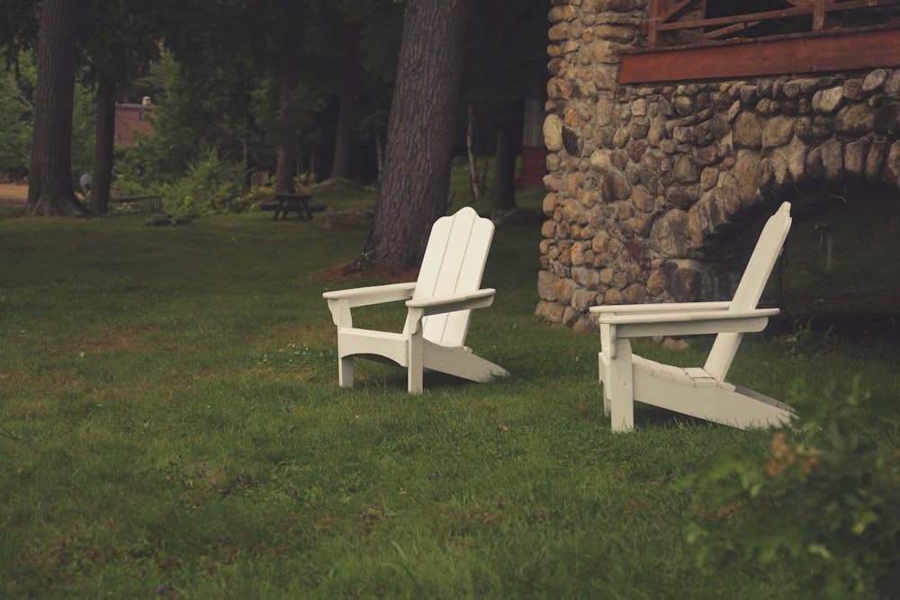 two white wooden armchairs on grasses