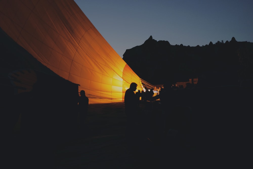 silhouette photo of people sitting near orange cover