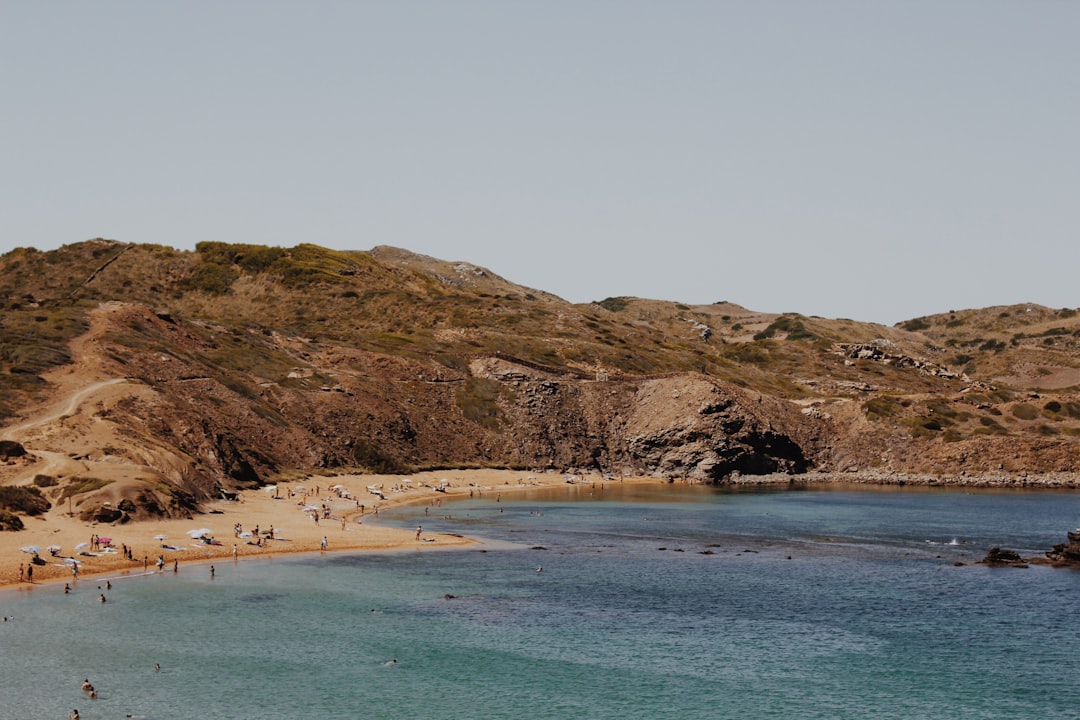 people near seashore swimming and standing during daytime photography