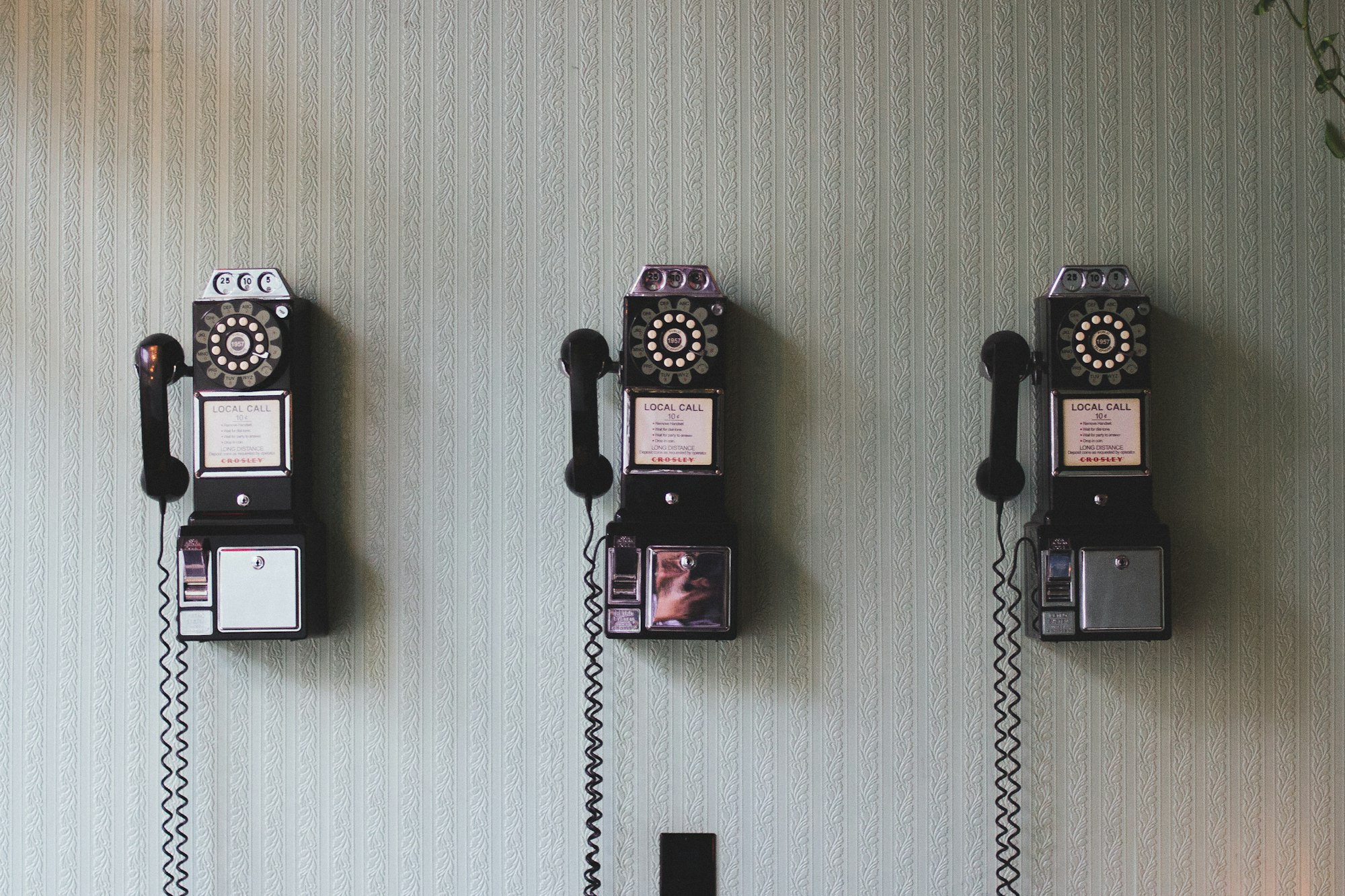 Three (really) old fashioned pay phones on a wall.