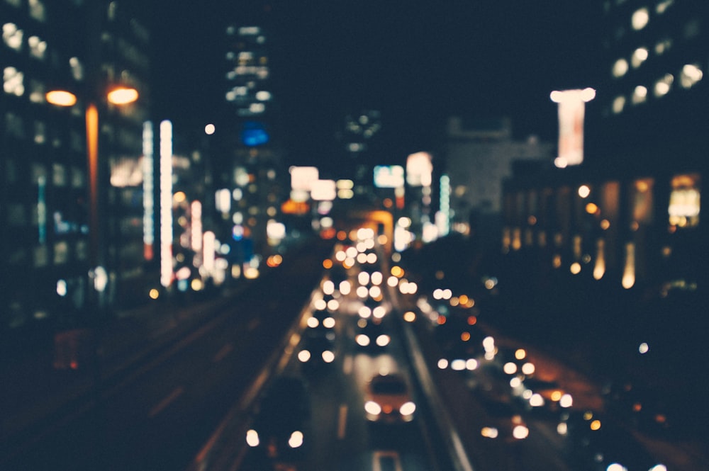Eine verschwommene Aufnahme einer Stadtstraße, die nachts von Gebäuden und Autos beleuchtet wird