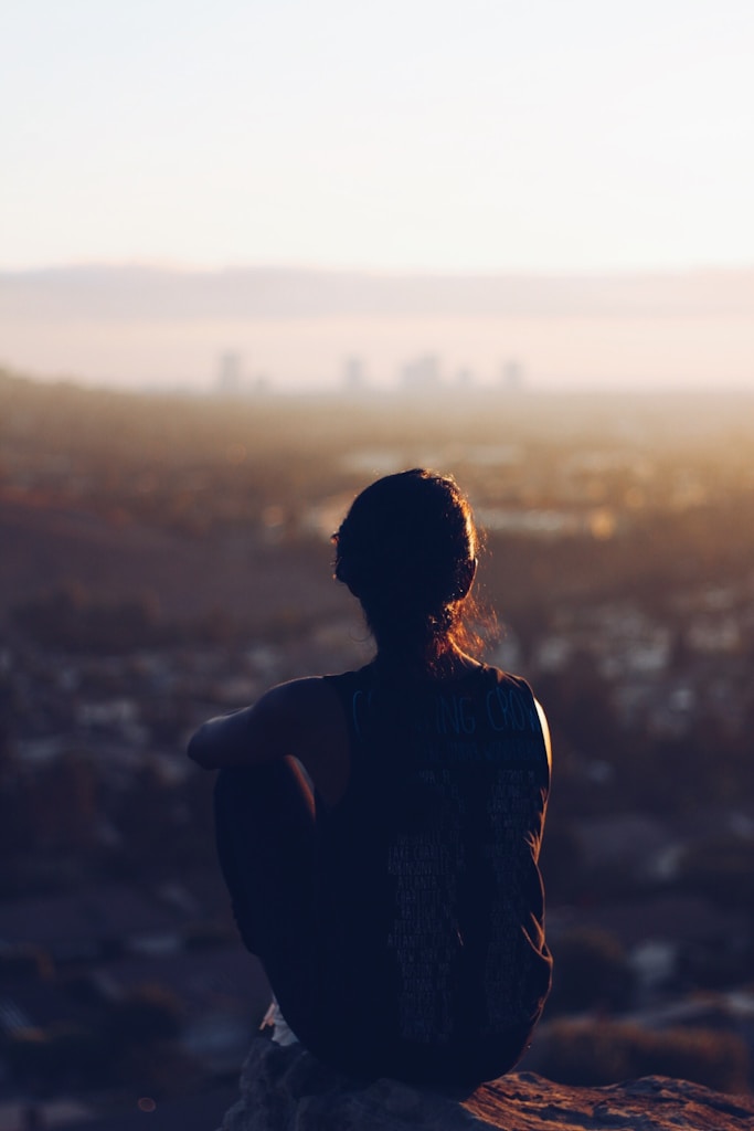 woman sitting on brown rock during daytime