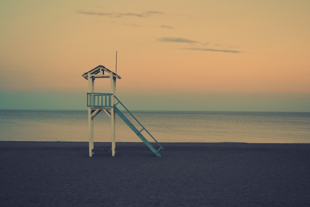 white wooden lifeguard station near seashore at golden hour