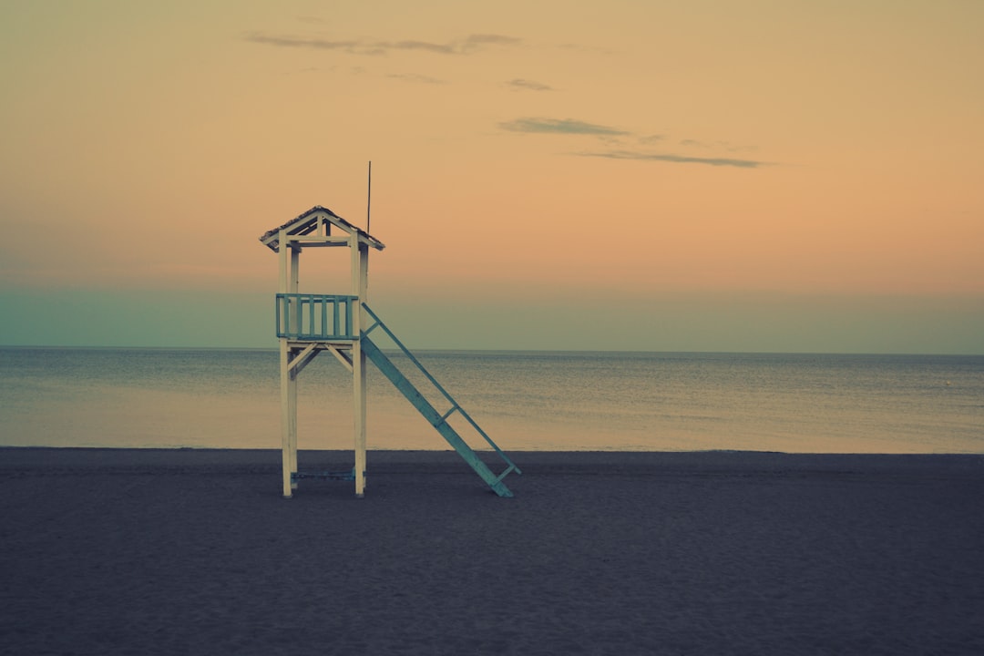white wooden lifeguard station near seashore at golden hour, lifeguard watchtower in beach